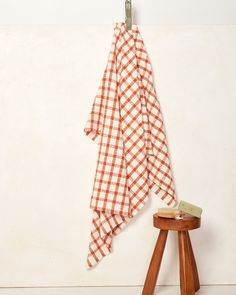 an orange and white checkered towel hanging on a clothes rack next to a stool