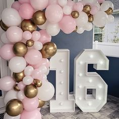 a large balloon arch with the number sixteen surrounded by pink, white and gold balloons