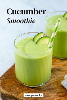 two glasses filled with cucumber smoothie on top of a wooden cutting board