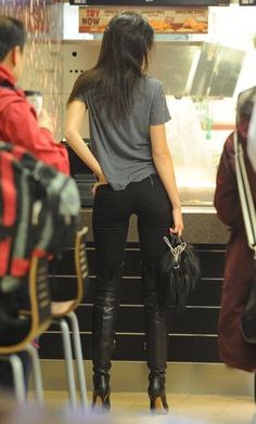 a woman standing in front of a counter with her hand on her hip while wearing black leather pants