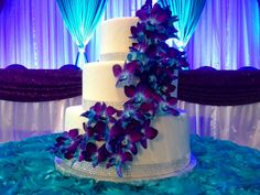 a wedding cake with purple and blue flowers on it