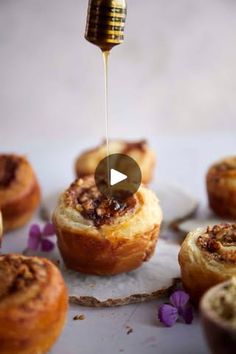 some food is being drizzled with honey on top of other muffins