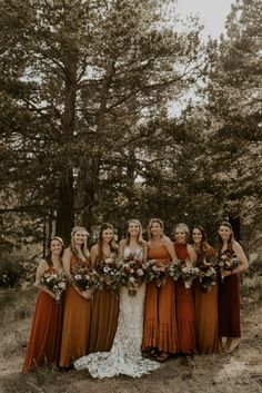 a group of women standing next to each other in front of some trees and grass