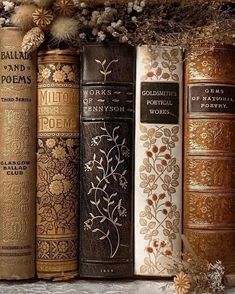 there are many old books lined up on the shelf in front of each other, all decorated with gold and white flowers