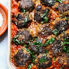 a casserole dish with meatballs covered in sauce and parmesan cheese