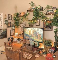 a computer desk topped with lots of potted plants and pictures on the wall above it