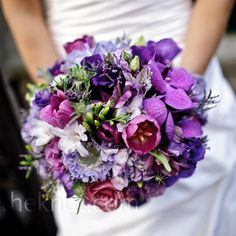 a bride holding a purple and red bouquet