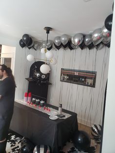 a man and woman standing in front of a table with black and white balloons on it