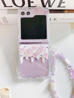 a cell phone case with pink and white flowers on the back, sitting next to a book