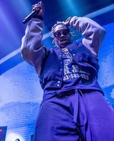 a man standing on top of a stage with his arms in the air while holding a microphone