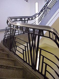 the stairs are made of metal and have black railings on each handrail, with white walls in the background