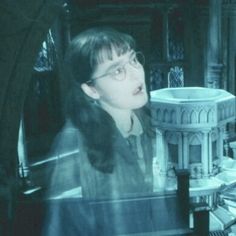 a woman with glasses is looking at the camera in front of a table that has books on it