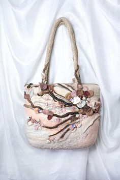 a handbag with flowers and leaves on it sitting on a white cloth covered surface