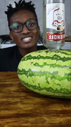 a man sitting in front of a watermelon with a bottle on top of it