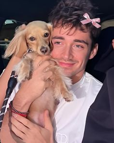 a man is holding a small dog in his arms and smiling at the camera while sitting in a car