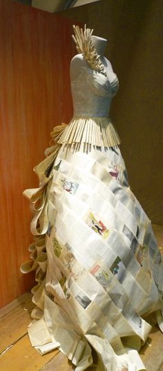 a dress made out of newspaper sitting on top of a wooden floor