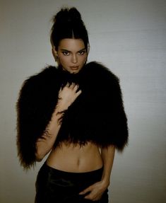 a woman wearing a black fur stole with her hands on her chest and looking at the camera