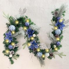 two christmas wreaths with blue and gold ornaments hanging on the wall next to each other