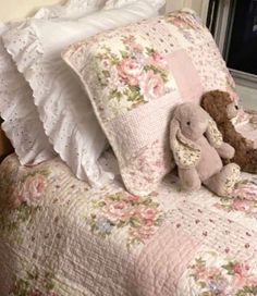 two teddy bears sitting on top of a bed next to pillows and pillowcases