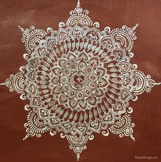 an intricately designed piece of artwork on a brown surface with white paint and designs