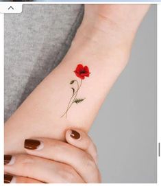 a woman's wrist with a red flower tattoo on the left side of her arm