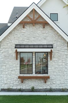 a white brick house with two windows and a wooden bench