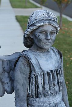 a statue of a woman with an angel wings on the side of a sidewalk in front of a house