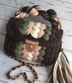 a handbag is sitting on the floor next to a chain and a tassel