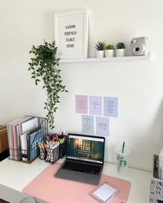 a laptop computer sitting on top of a pink desk next to a potted plant