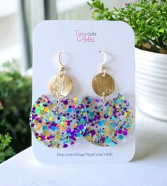 Confetti Lightweight Fun Glitter Earrings, the perfect accessory to add a pop of joy and sparkle to any outfit! Crafted with care from high-quality acrylic, these earrings are both lightweight and durable, ensuring comfort and longevity with every wear. Measuring at a delightful 1.40 inches in diameter and 2-2.25 inches in height, these round earrings boast a playful yet sophisticated design. Each earring is adorned with a mesmerizing array of vibrant confetti-style glitter and gold brass brushe Multicolor Round Earrings For Birthday, Glitter Hoop Earrings Gift, Hoop Jewelry With Glitter For Gifts, Playful Gold Earrings For Party, Fun Gold Jewelry For Party, Multicolor Fun Hoop Earrings For Party, Fun Multicolor Hoop Earrings For Party, Multicolor Circle Earrings For Party, Fun Small Hoop Earrings As Gift