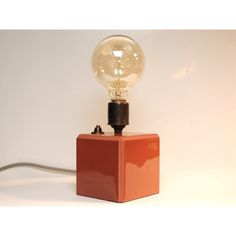 an orange square lamp with a light bulb on top