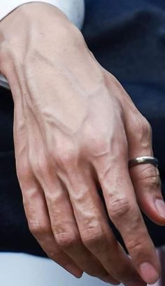 a close up of a person's hand with a ring on their finger and an object in the background