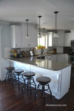 a kitchen island with four stools in front of it