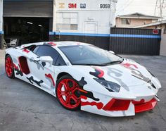 a white and red sports car parked in front of a garage door with graffiti on it