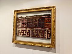 an old rug is hanging on the wall next to a gold framed frame with it's border