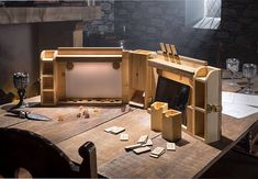 a wooden table topped with lots of clutter next to a fire place filled with candles