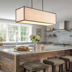 a kitchen island with four stools in front of it and a light fixture hanging from the ceiling