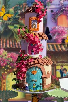 the cake is decorated with flowers and fairy land decorations on it's sides, including a door