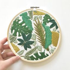 a hand is holding up a green and yellow embroidery