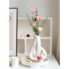 a vase with flowers in it sitting on a white table next to a framed photograph