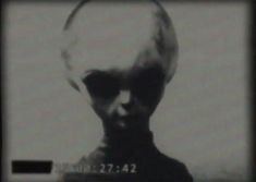 a black and white photo of an alien looking man's head in the dark