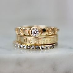 three gold wedding rings with diamond accents on the bottom and one has a small white diamond in the middle