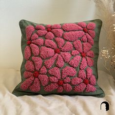 a pillow with pink flowers on it sitting on a bed