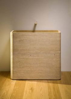 a wooden box sitting on top of a hard wood floor next to a white wall