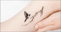 a small tattoo on the side of a woman's stomach with a bird flying over it