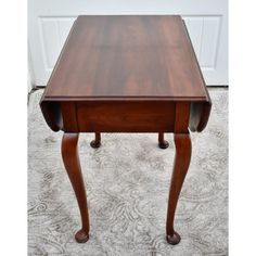 a wooden table sitting on top of a carpeted floor next to a white door