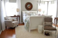 a white bed sitting in a bedroom on top of a hard wood floor next to a chair