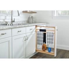 a kitchen with white cabinets and wood flooring has an open dish rack in the corner