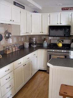 a kitchen with white cabinets and black counter tops