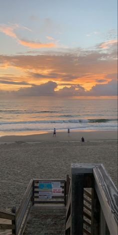 people are walking on the beach at sunset